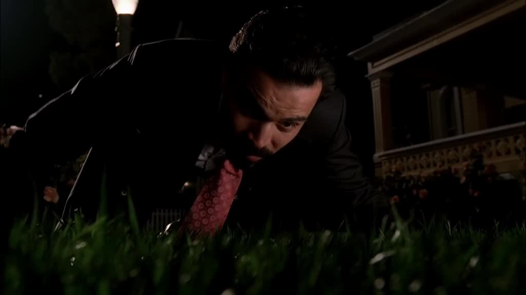CARLOS kneels on the sidewalk, putting his  face close to the grass.jpg