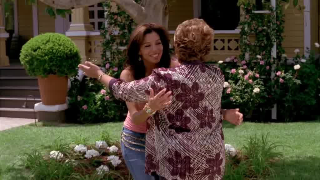 Mama Solis drops her bags at her side and holds her arms out to Gabrielle.jpg