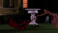 S01E01 She pushes the machine onto the grass and begins to mow the lawn, tottering along in her high heels and party dress