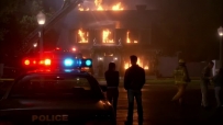 S01E01 The camera pans out, showing them standing together from behind, both watching the burning house side by side